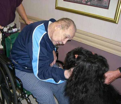 A GFMDC dog brightens the day of a gentleman in a wheel chair.